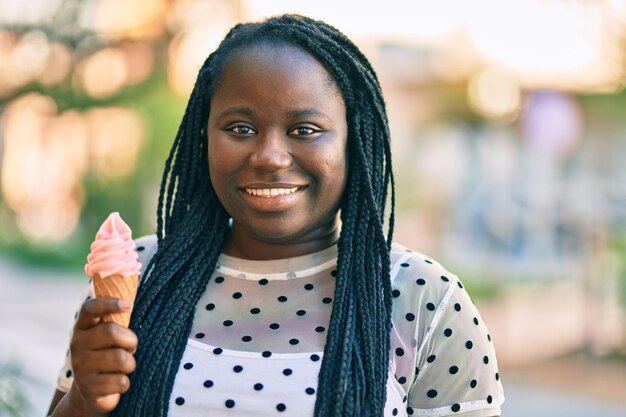 街でアイスクリームを食べて幸せに微笑む若いアフリカ系アメリカ人女性。