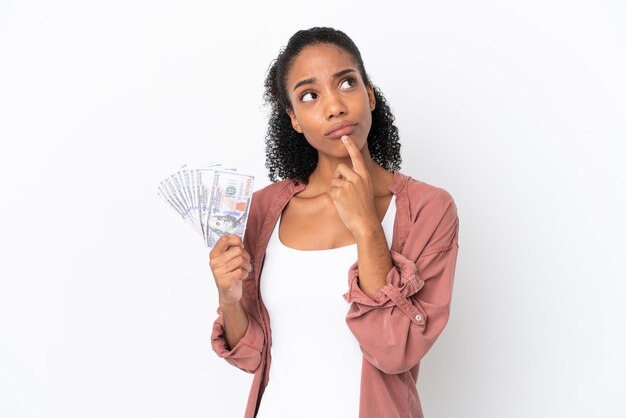 Young African American woman taking a lot of money isolated on white background having doubts while looking up