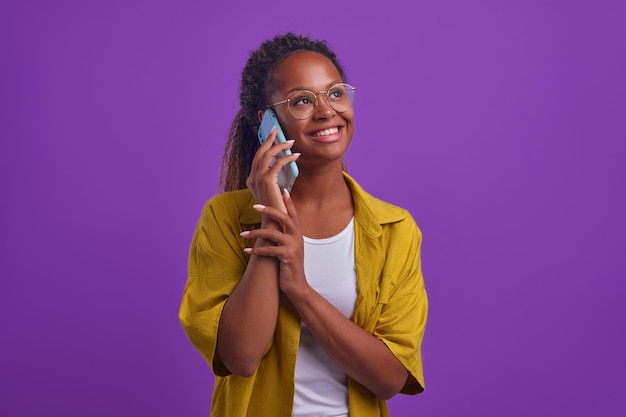 Photo young african american woman talking on phone and smiling stands in studio