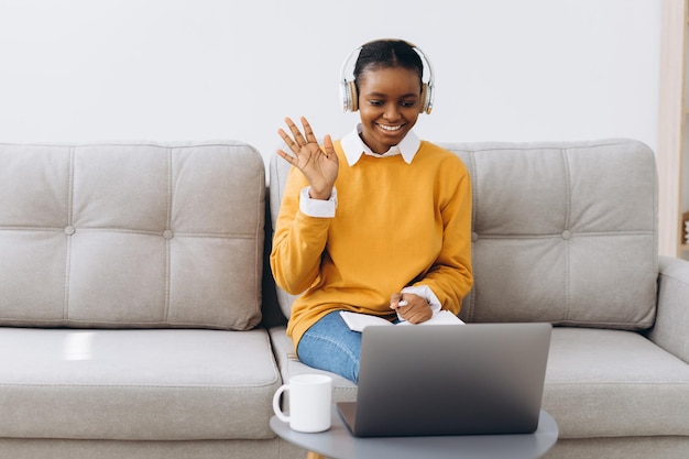 Young African American woman talking on video call in living room at home, distance learning concept from home.