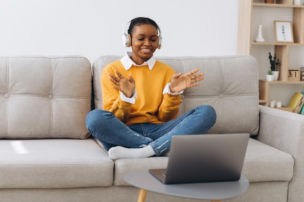 Giovane donna afroamericana che parla in videochiamata in soggiorno a casa concetto di apprendimento a distanza da casa