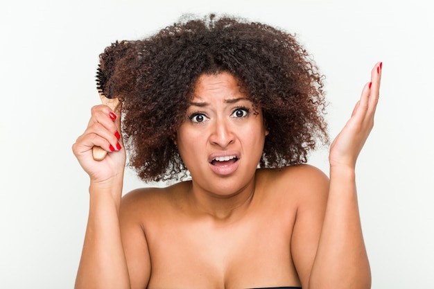 Young african american woman trying to brush her curly hair