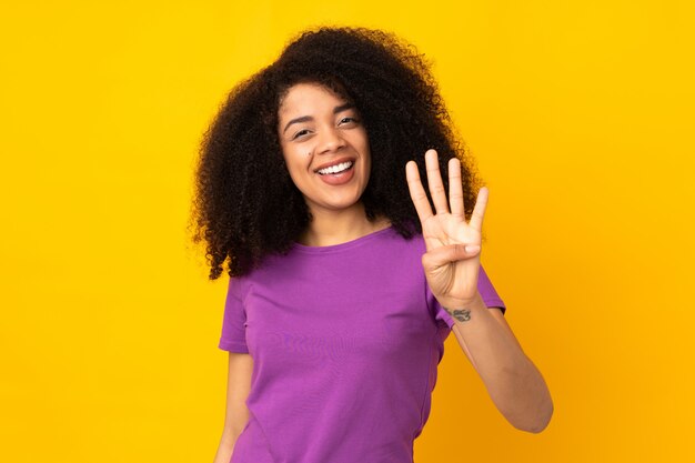 Young african american woman over wall happy and counting four with fingers