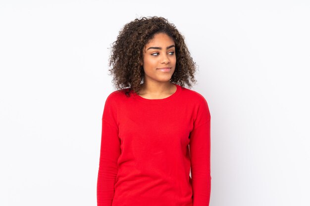 Young African American woman on wall having doubts while looking side