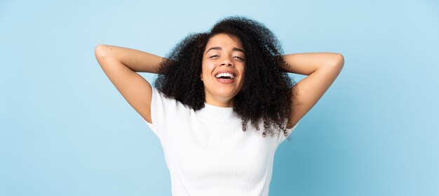 Young african american woman over wall laughing