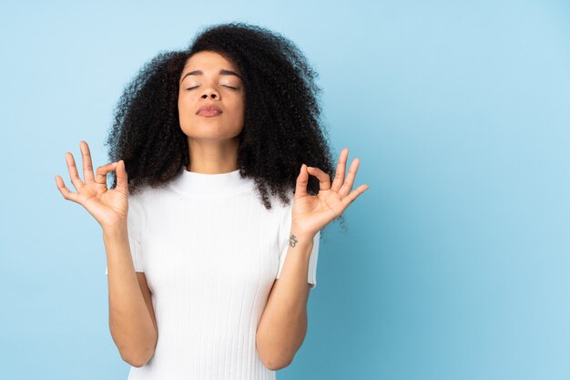 Young african american woman over wall in zen pose