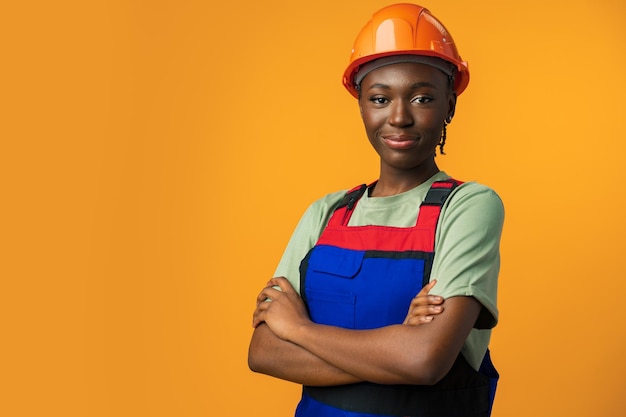 Photo young african american woman wearing architect hardhat against yellow background