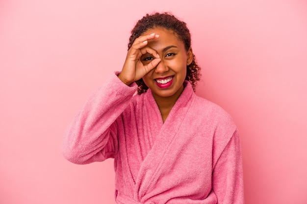 Young african american woman wearing a bathrobe isolated on pink background excited keeping ok gesture on eye.