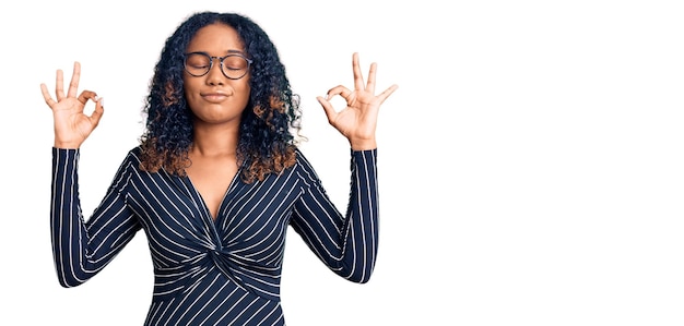 Young african american woman wearing casual clothes and glasses relax and smiling with eyes closed doing meditation gesture with fingers. yoga concept.