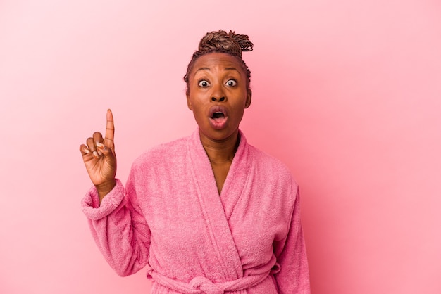 Young african american woman wearing pink bathrobe isolated on pink background having some great idea, concept of creativity.