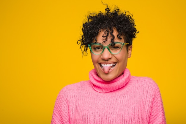 Foto giovane donna afroamericana che indossa un maglione rosa divertente e amichevole che attacca fuori lingua.