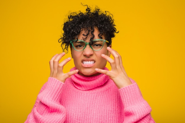 Молодая женщина афроамериканцев, носить розовые свитер расстроен, кричать с напряженными руками.