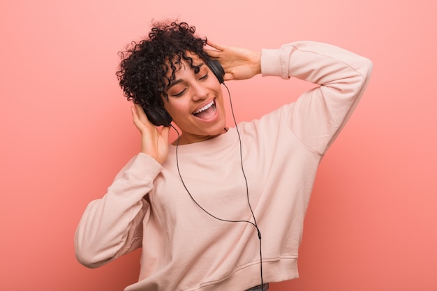 Young african american woman with a birthmark dancing and listening to music with a headphone