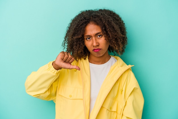 Young african american woman with curly hair isolated on blue background showing thumb down, disappointment concept.