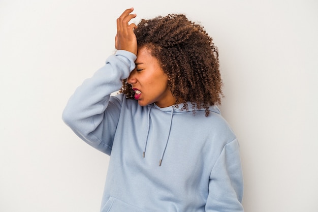 Young african american woman with curly hair isolated on white background forgetting something, slapping forehead with palm and closing eyes.