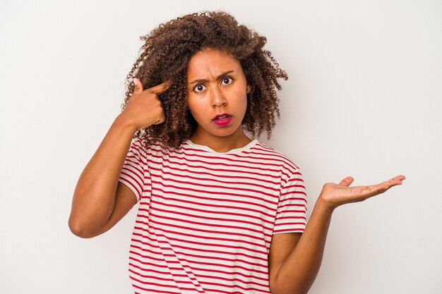 Young african american woman with curly hair isolated on white background holding and showing a product on hand.