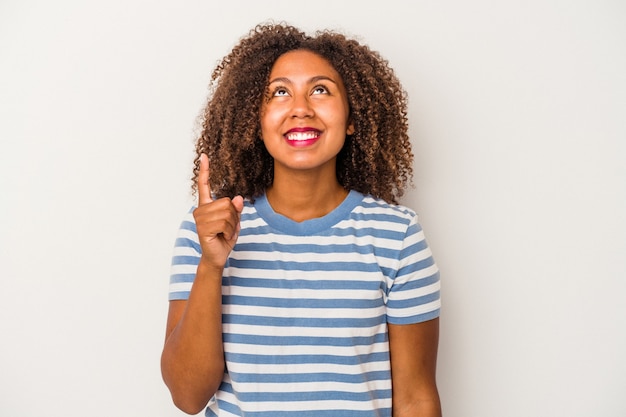 흰색 배경에 곱슬머리가 격리된 젊은 아프리카계 미국인 여성은 두 앞 손가락으로 빈 공간을 보여주고 있음을 나타냅니다.