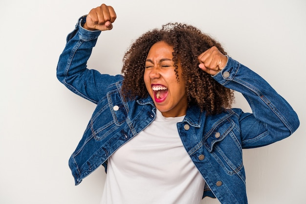 Young african american woman with curly hair isolated on white background raising fist after a victory, winner concept.