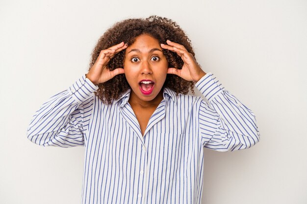 Young african american woman with curly hair isolated on white background receiving a pleasant surprise, excited and raising hands.