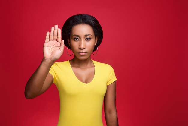 Young african american woman with a decisive gesture raised her palm forward. Stop gesture.