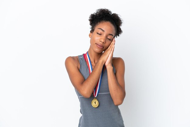 Молодая афро-американская женщина с медалями, изолированными на белом фоне, делая жест сна в достойном выражении