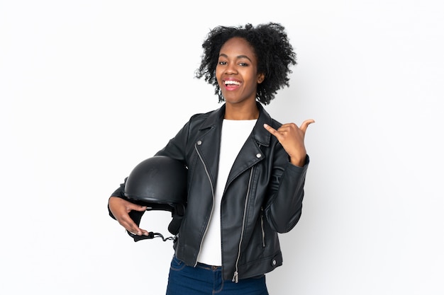 Young African American woman with a motorcycle helmet on white wall making phone gesture