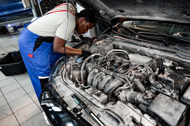 Photo young african auto mechanic checking car engine under the hood in auto service