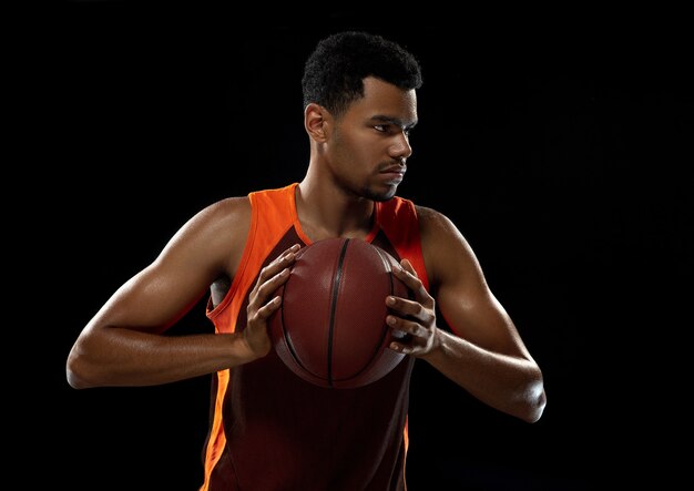 Photo young african basketball player training on black studio background.