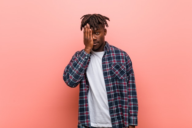 Young african black man having fun covering half of face with palm.