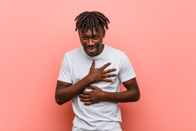 Young african black man laughs happily and has fun keeping hands on stomach.