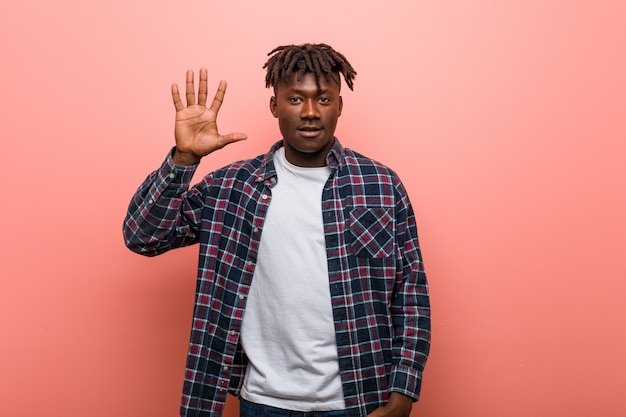 Young african black man smiling cheerful showing number five with fingers.