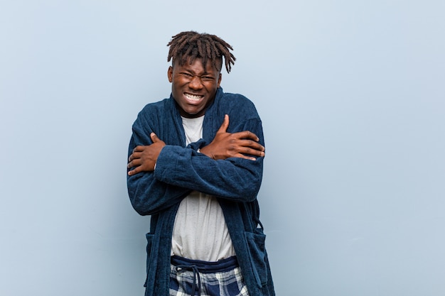 Young african black man wearing pajama going cold due to low temperature or a sickness.