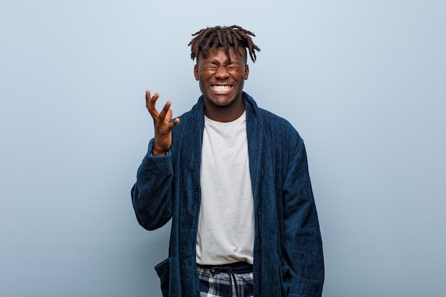 Young african black man wearing pajama screaming with rage.