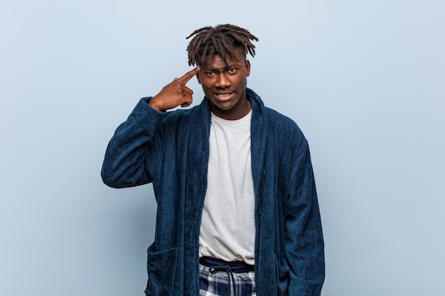 Young african black man wearing pajama showing a disappointment gesture with forefinger.