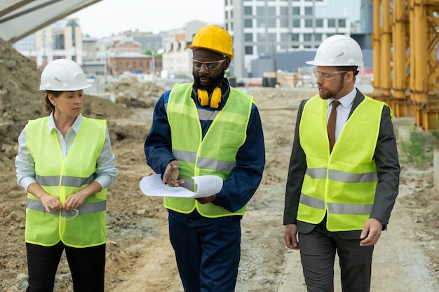 Young African builder explaining sketch of construction to colleagues at meeting