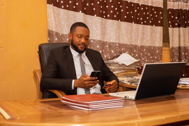 A young african business man using his credit card and mobile phone online banking concept