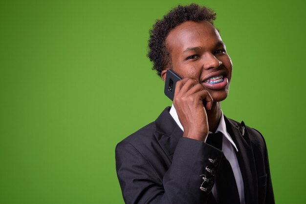 Young African businessman against green wall