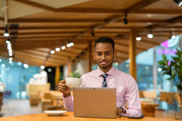 Giovane uomo d'affari africano in una caffetteria utilizzando il computer portatile