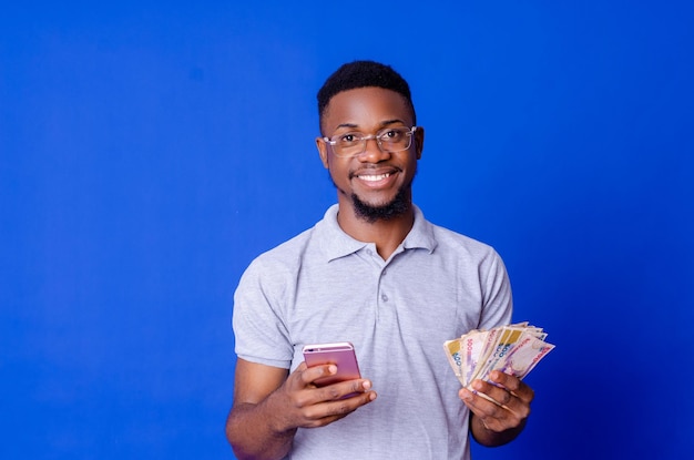 Young african businessman holding a lot of money and using his phone