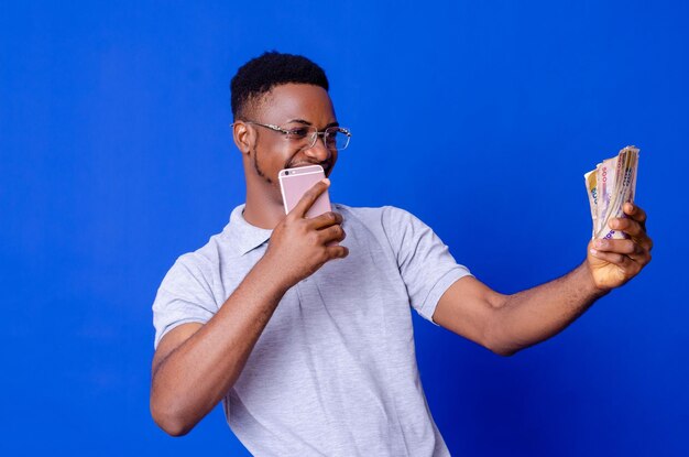 Young african businessman holding a lot of money and using his phone