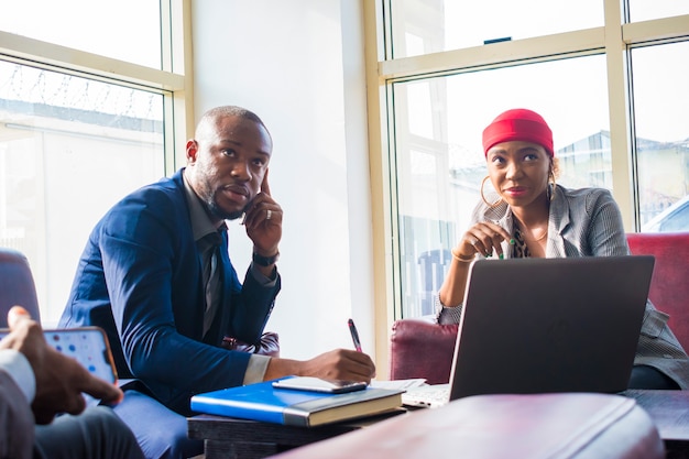 Young african businessman making a call while his coworker waits for him.