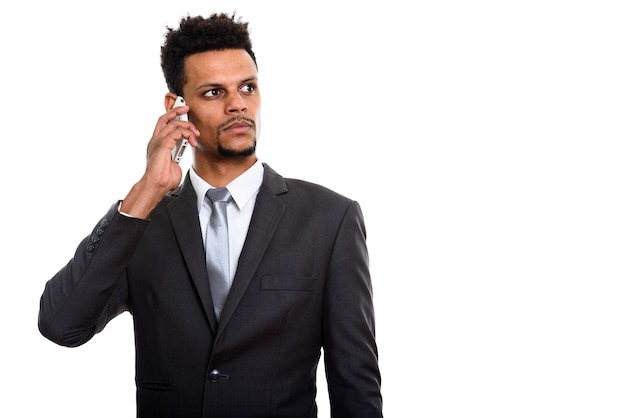 Молодой африканский бизнесмен разговаривает по мобильному телефону, думая, изолированные на белом