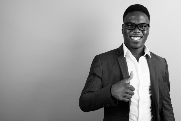 young African businessman wearing suit against white wall. black and white