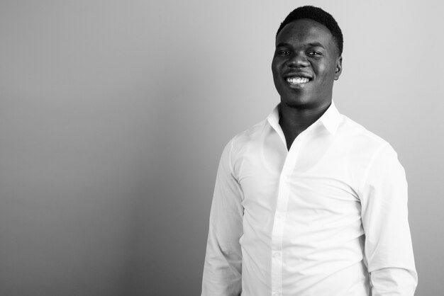 young African businessman wearing white shirt against white wall. black and white