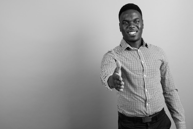 young African businessman with afro hair against white wall. black and white