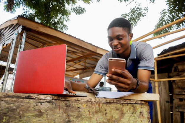 Photo young african carpenter standing holding working calling laptop