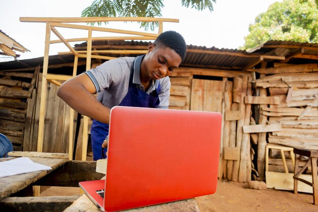 Photo young african carpenter standing holding working calling laptop