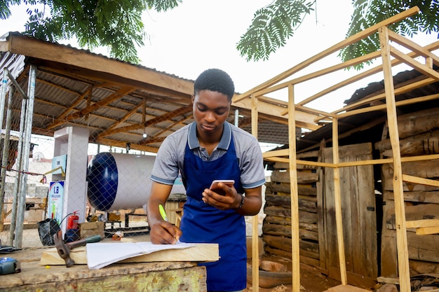 Молодой африканский плотник стоит и держит рабочий вызов