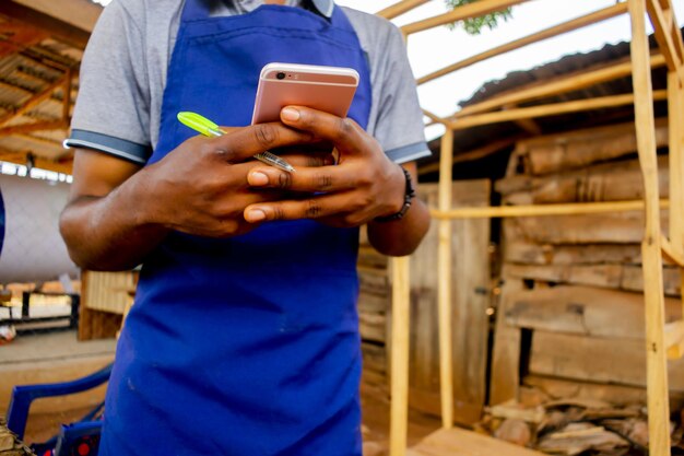 Молодой африканский плотник стоит и держит рабочий вызов