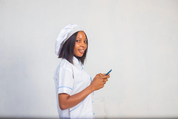 Young african chef smiling while using his phone on social media